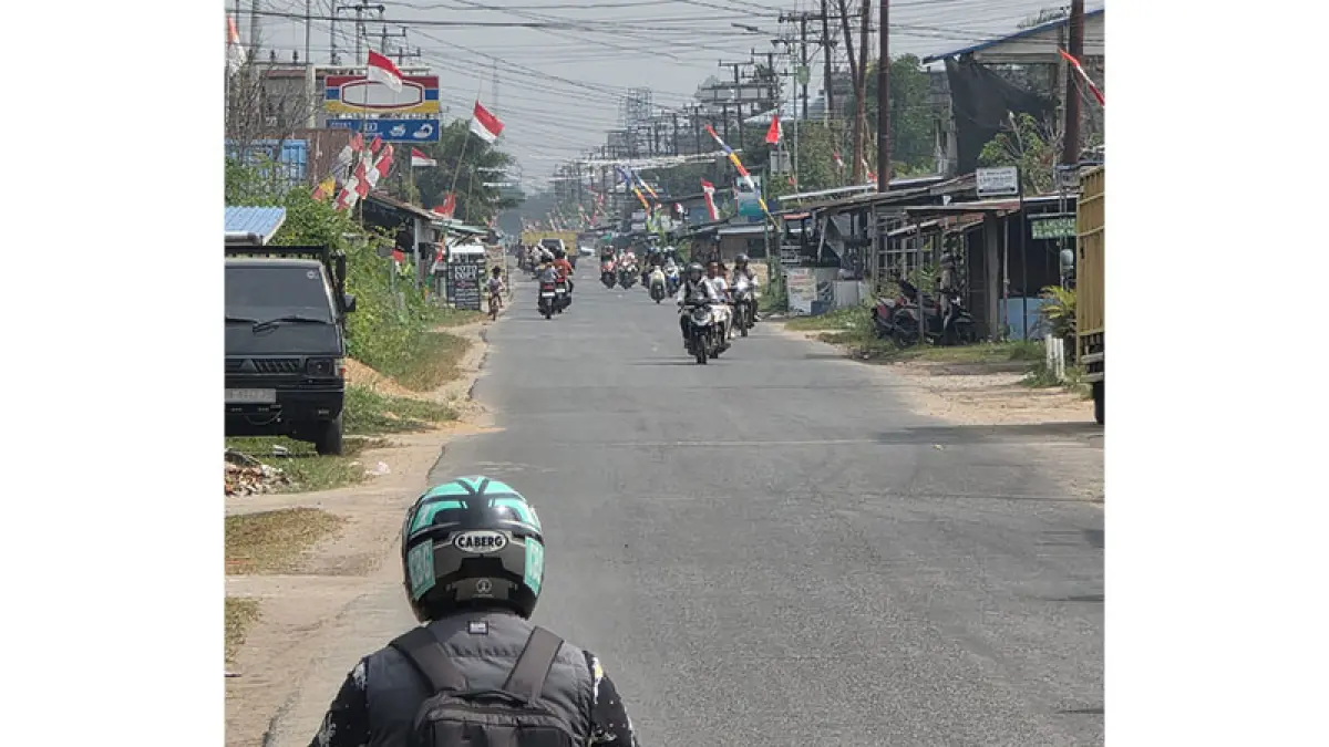 Pengemudi sepeda motor melintas di bawah kabut asap tipis di langit Kota Tembilahan. (Istimewa)