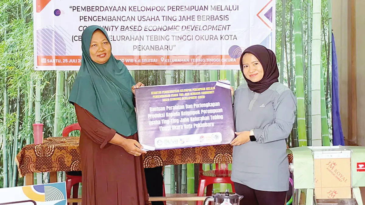SERAHKAN PERALATAN: Ketua Tim Program PkM Unri Risky Arya Putri SSos MSi menyerahkan hibah peralatan produksi secara simbolis kepada Ketua Kelompok Perempuan UMKM Ting Jahe di Tebing Tinggi Okura, Pekanbaru, Sabtu (25/7/2026) lalu.(Tim PkM Unri untuk Riau Pos)
