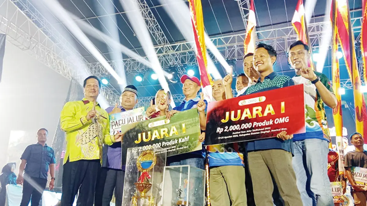 Pelaksana Tugas Bupati Kuantan Singingi Muklisin menyerahkan piala bergilir Menteri Pariwisata RI dan piala tetap, tonggol juara kepada perwakilan Jalur Alam Cahayo Tuah Nagori dari Kecamatan Cerenti selaku juara Festival Pacu Jalur Tradisional 2026 di Taman Jalur Telukkuantan, Ahad (23/8/2026).(DESRIANDI CANDRA/RIAUPOS)