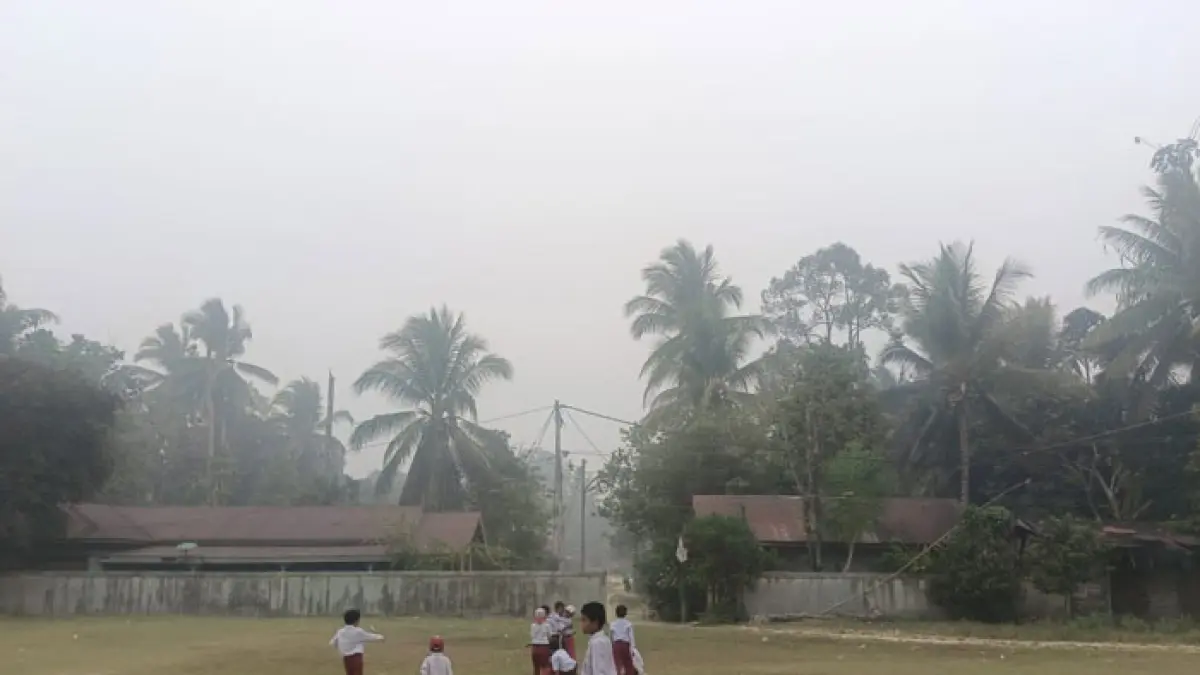 Murid SD di Kecamatan Batang Cenaku tepatnya di Desa Alim, berjalan di halaman sekolah dengan kondisi asap tebal, Senin (24/8/2026). (Warga Batang Cenaku untuk Riaupos.co)