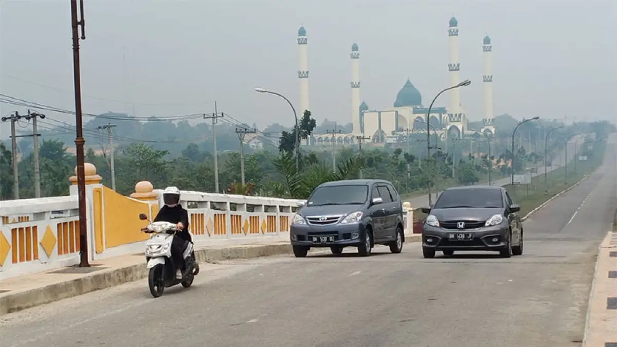 Pengedara sepeda motor  melintasi Jalan Sultan Syarif Hasyim Pangkalan Kerinci yang mulai diselimuti&nbsp;kabut asap dampak kian meluasnya kathuta di Pelalawan, Selasa  (25/8/2026) sore. (M Amin Amran)