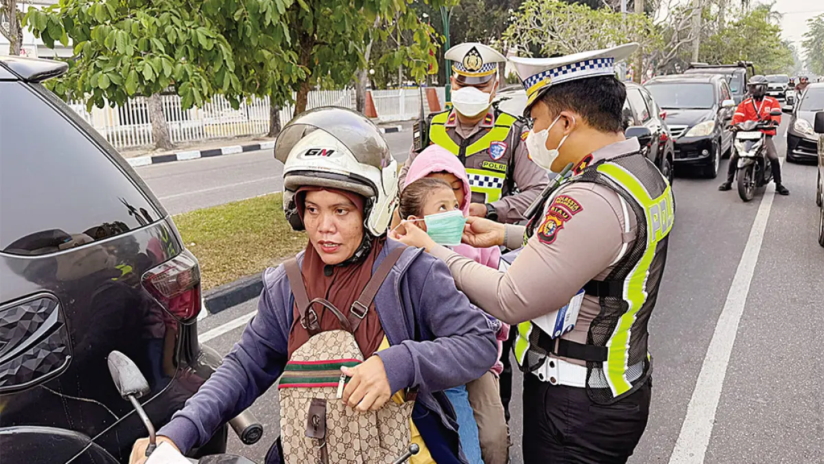 BAGIKAN MASKER: Petugas kepolisian membagikan masker kepada pengendara yang melintas di Jalan Diponegoro Pekanbaru, Selasa (25/8/2026). (Satlantas Polresta Pekanbaru untuk riau pos)