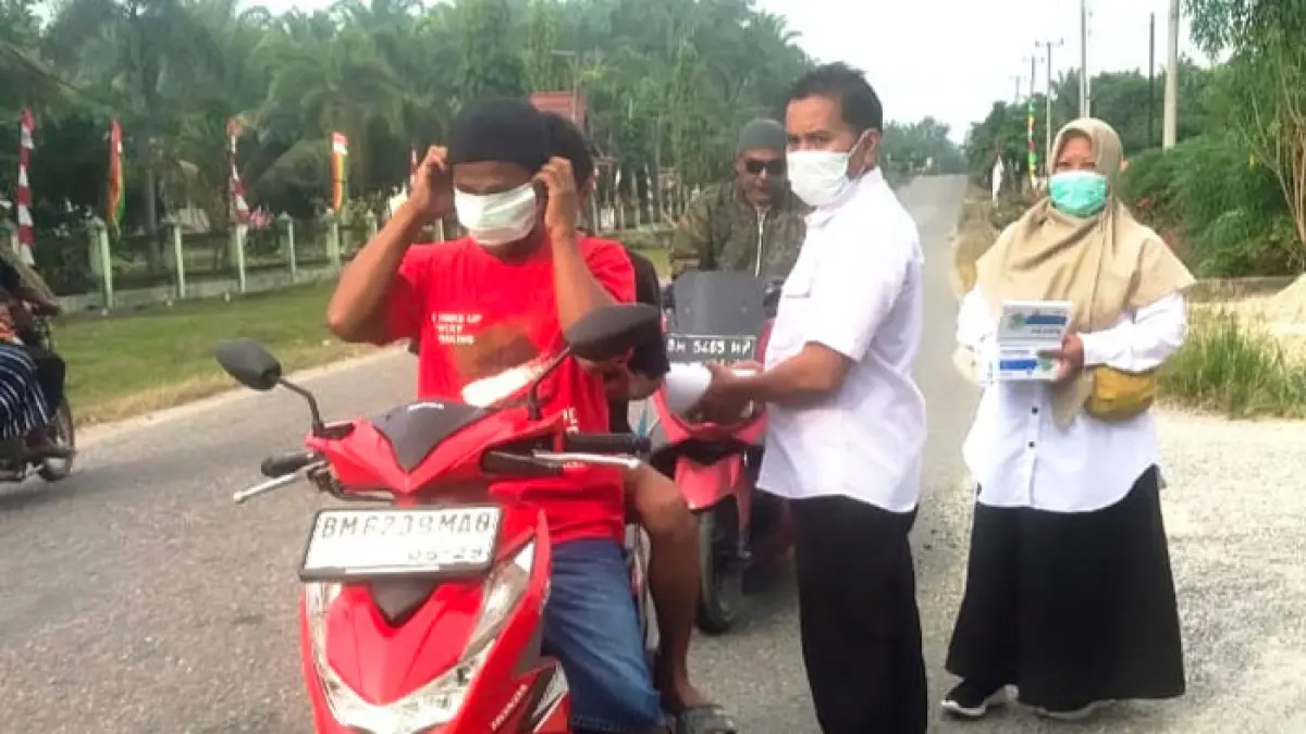 Pegawai Puskesmas Pagaran Tapah Darussalam membagikan masker gratis kepada warga dan pengendara bermotor, Rabu (26/8/2026). (Dinas Kesehatan Rohul untuk Riaupos.co)