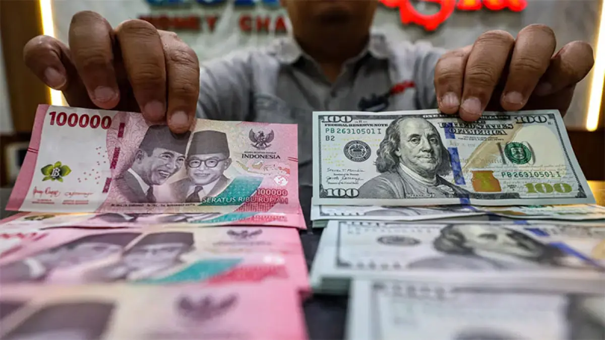 Karyawan salah satu gerai penukaran mata uang asing di Jakarta, menunjukan mata uang dolar AS dan rupiah, belum lama ini. (Salman Toyibi/Jawa Pos)

