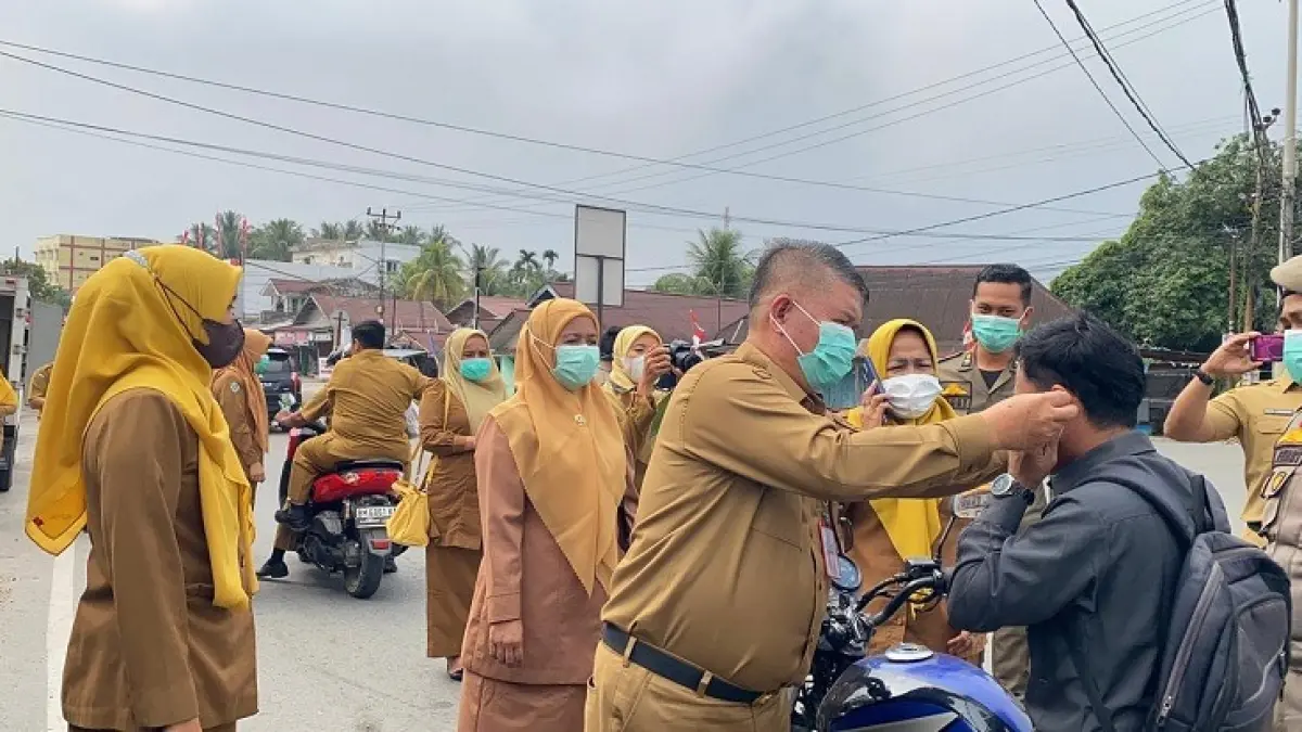 Pj Sekda Kuansing Drs Muradi MSi membagikan masker pada pengguna jalan di simpang Tugu Pelajar Simpang Tiga Telukkuantan, Senin (31/8/2026). (Desriandi Candra/Riaupos.co)