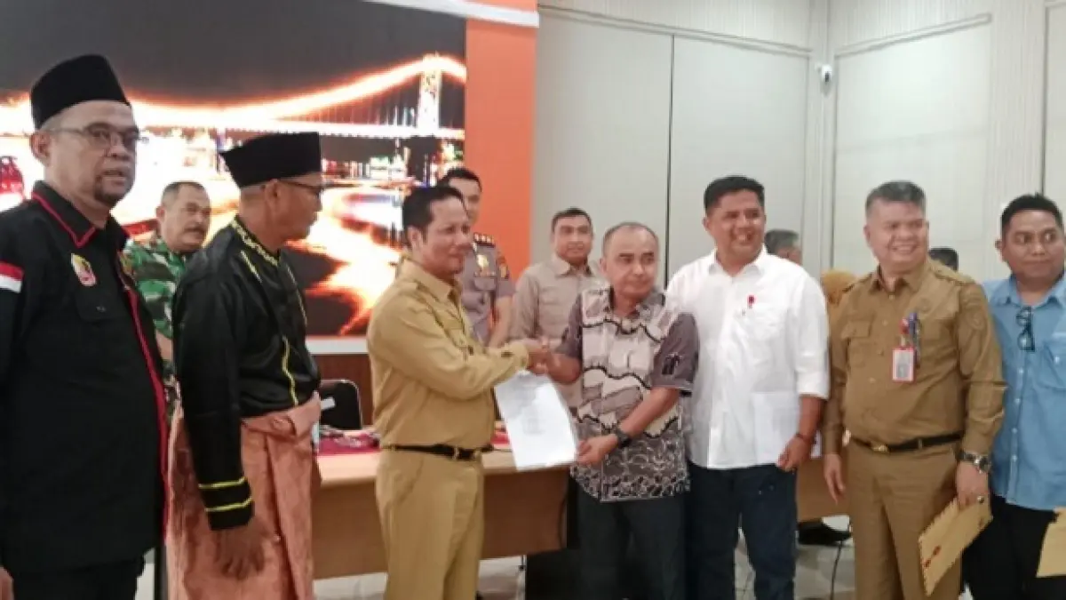 SHR Manager RAPP Raja Elwan Jumanri menyerahkan kesepakatan tahun 1998 antara PT RAPP dan ninik mamak Desa Koto Baru, pada Plt Bupati H Muklisin usai mediasi di multimedia Kantor Bupati Kuansing, Senin (31/8/2026). (Istimewa)