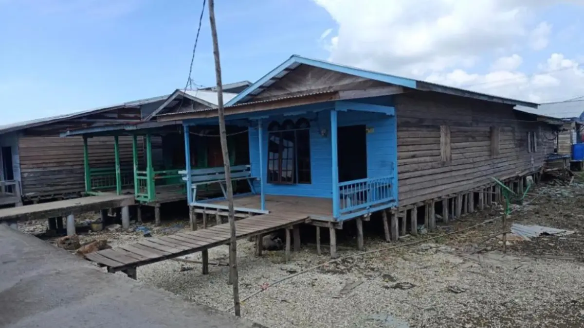 Rumah panggung tradisional berbahan kayu, dengan teras khas di bagian depan dan tiang pancang kayu yang menopang seluruh bangunan.(TIM PENELITI FT UNILAK UNTUK RIAUPOS.CO)