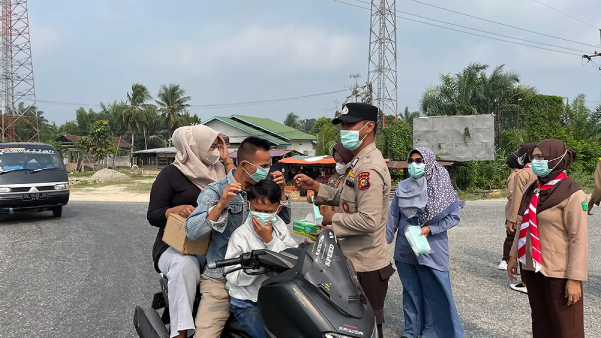 BAGIKAN MASKER: Tim Dinas Kesehatan Siak bersama Polri dan Pramuka membagikan masker kepada pengendara di sejumlah titik di Kabupaten Siak, Sabtu (5/9/2026). (Diskes siak untuk riau pos)