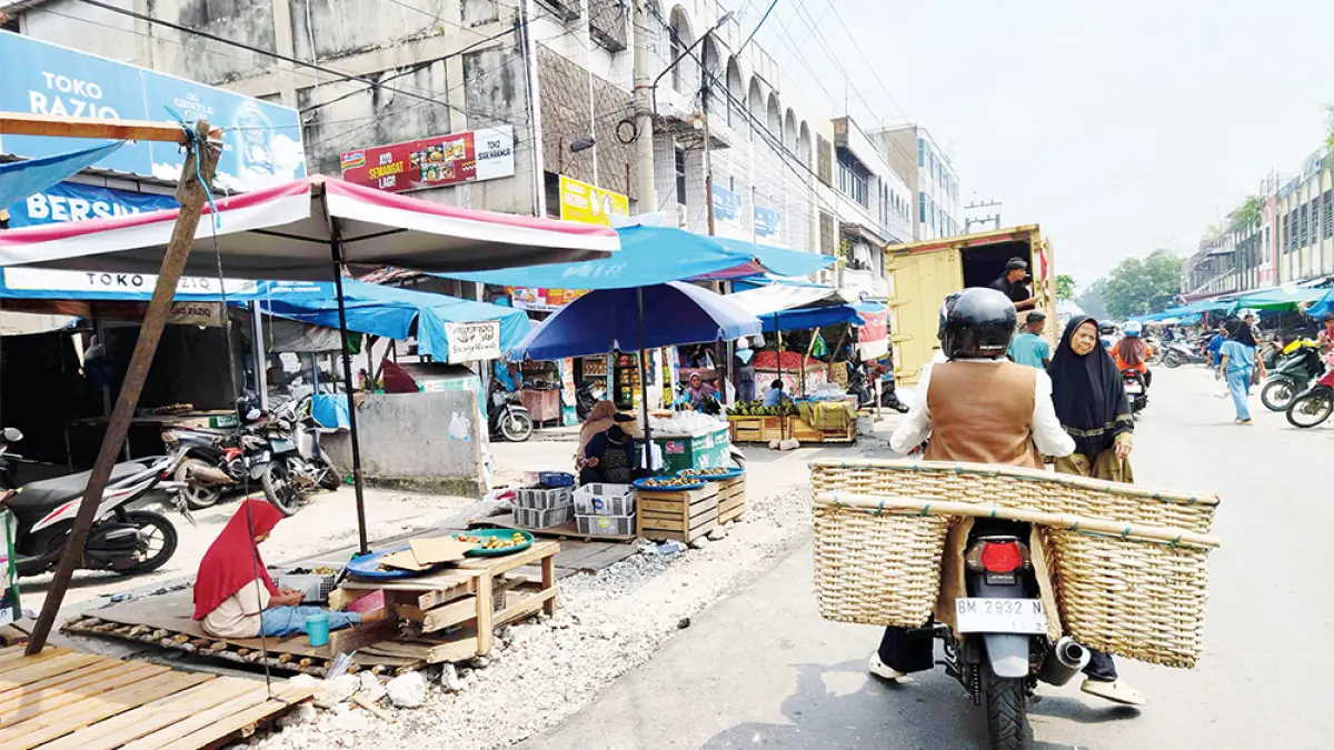 KEMBALI JUALAN: Pedagang kembali berjualan dengan membuat lapak kayu di atas aliran drainase Jalan Teratai yang baru selesai diaspal ulang,  Ahad (6/9/2026). (EVAN GUNANZAR/RIAU POS)