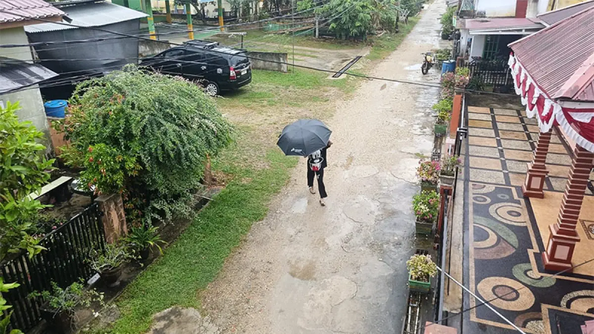 Salah seorang warga melintas menggunakan payung saat hujan turun, Jumat (11/9/2026). Foto Raja Kasmedi