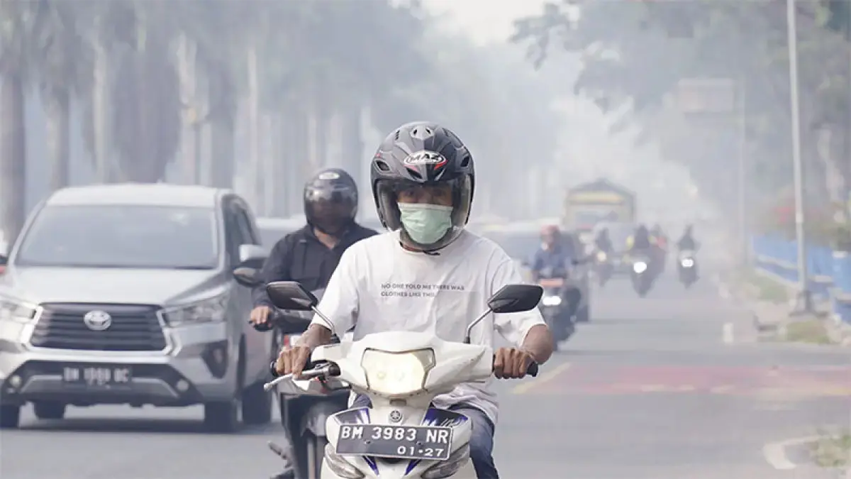 Pengendara sepeda motor memakai masker ketika melintas di Jalan Jenderal Sudirman, Pekanbaru yang diselimuti kabut asap, bebarapa waktu lalu. (Dok Riaupos.co)