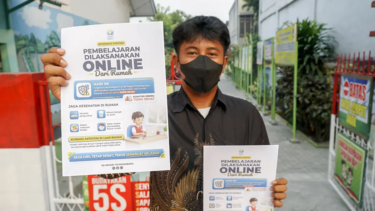 Petugas SDN 115 Pekanbaru memperlihatkan pengumuman pelaksanaan pembelajaran jarak jauh atau secara daring di saat kabut asap menyelimuti Pekanbaru, baru-baru ini. (MHD AKHWAN/RIAU POS)