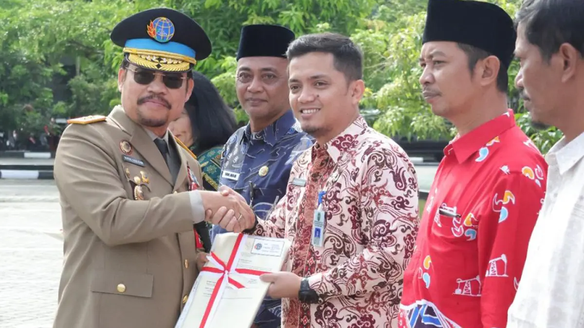 SERAHKAN SERTIFIKAT: Kepala Kantor Wilayah (Kanwil) BPN Provinsi Riau Nurus Sholichin (kiri) menyerahkan secara simbolis sertifikat PTSL kepada masyarakat dan instansi dalam rangka memperingati Hari Agraria dan Tata Ruang Nasional (Hantaru) di halaman Kantor Pertanahan Pekanbaru, Kamis (24/9/2026).(Prapti Dwi Lestari/riau pos)