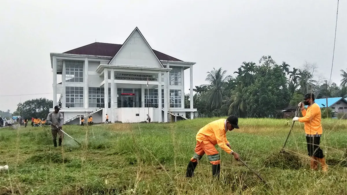 Petugas kebersihan melakukan pemotongan rumput di halaman Dinas Perpustakaan dan Kearsipan Kabupaten Kepulauan Meranti, Kamis (8/10/2026). Penataan lingkungan dilakukan untuk menjaga kebersihan dan kenyamanan fasilitas perpustakaan sebagai ruang publik. (Wira Saputra)