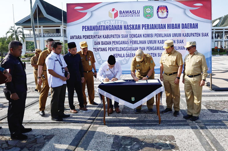 Bupati Siak Alfedri didampingi Wabup Husni Merza dan Sekda Arfan Usman menandatangani NPHD dengan Ketua KPU Ahmad Rizal disaksikan Ketua Bawaslu Fandli di halaman Kantor Bupati Siak, Senin (13/11/2023).