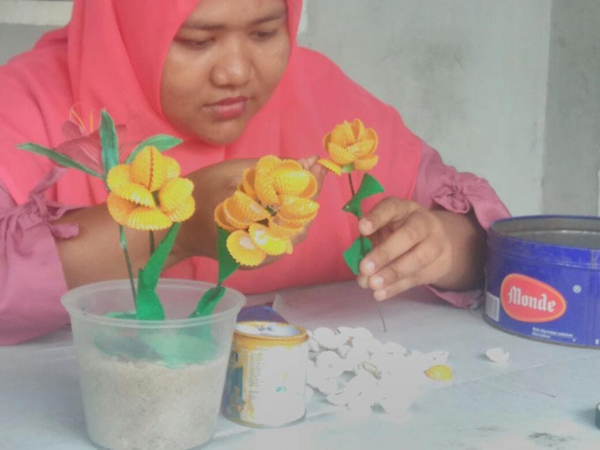 Tria tampak mencontohkan teknik pembuatan bunga dari limbah cangkang kerang dara yang ia dapat dari limbah disekitar rumah, Sabtu (21/8/2021).