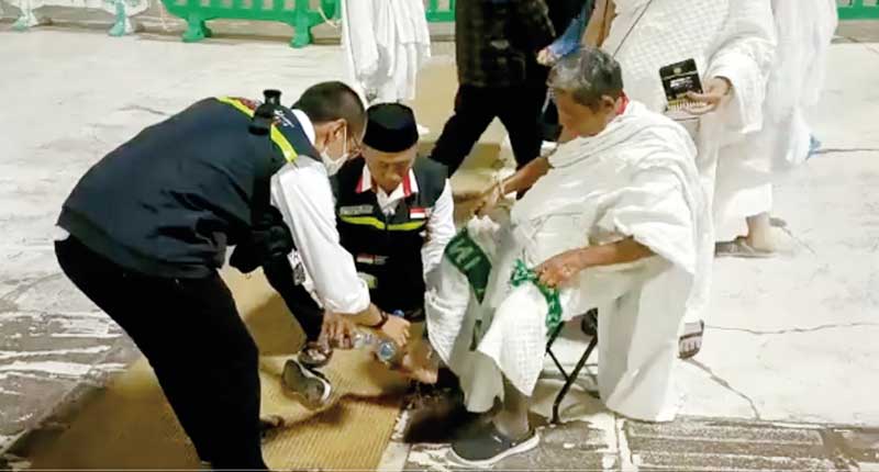 Petugas haji Indonesia membantu menyiram kaki jemaah calon haji lanjut usia dengan air karena kepanasan akibat cuaca terik di Makkah mencapai 44 derajat celcius.