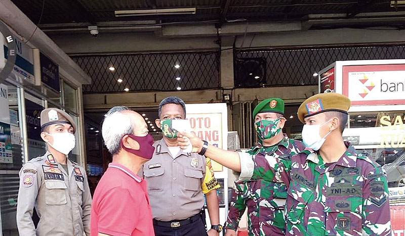 Petugas tim gabungan mengecek suhu tubuh warga saat menyosialisasikan Perwako 104/2020 tentang Perilaku Hidup Baru (PHB) di sejumlah tempat usaha di Jalan Jenderal Sudirman, Senin (15/6/2020).Â Sosialisasi akan dilakukan selama sepekan.(ALINURMAN/RIAUPOS.