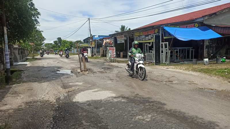 Dua batang kayu ditancapkan di lubang Jalan Kesadaran, Tangkerang Labuai, Kecamatan Bukit Raya sebagai tanda agar pengguna jalan berhati-hati karena kondisi jalan yang rusak, Selasa (11/7/2023).