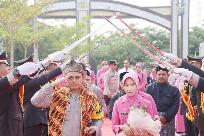 Kapolres Rohul AKBP Budi Setiyono bersama istri Ina Budi disambut ratusan personel dengan pedang pora pada upacara welcome and farawel parade dalam sertijab di Mapolres Rohul, Senin (17/4/2023).