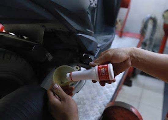 Seorang mekanik memasukkan AHM OIL tipe SPX2 dengan kemasan terbaru berukuran 0,65L sesuai keperluan sepeda motor skutik Honda bermesin eSP 110cc generasi terbaru.