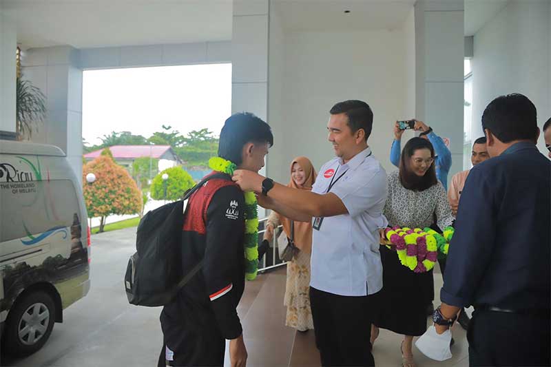 Kadispora Riau Boby Rachmat mengalungkan bunga kepada Muhammad Hafis, atlet sepak takraw Riau peraih medali emas dan perak di SEA Games saat kedatangan di Bandara SSK II Pekanabaru, Jumat (26/5/2023).