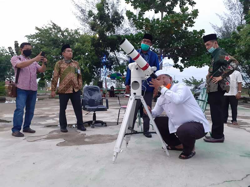 Wabup Rohil Drs H Jamiludin melihat hilal mengunakan alat teleskop di depan kantor kemenag Rohil di Batu Enam, Bagansiapiapi, Kamis (23/4) petang. Foto: ZULFADHLI/RIAUPOS.CO