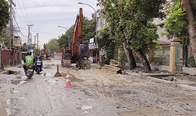 Pengendara kesulitan saat melintas di Jalan Melur yang rusak parah akibat adanya pengerjaan proyek Sistem PengoÂ­laÂ­han Air Limbah Domestik Terpadu (SPALD-T), Selasa (24/1/2023). Kondisi jalan yang rusak ini menyebabkan jalan menjadi licin.