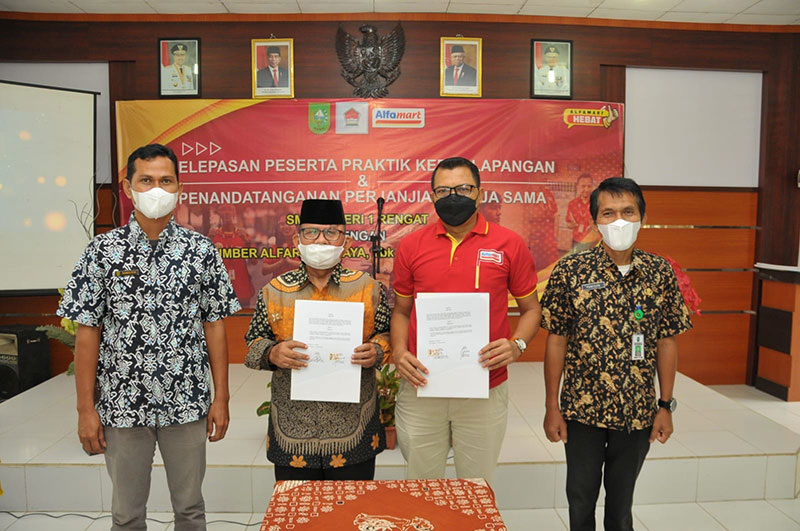 Kepala SMKN 1 Rengat, Drs Ahmad Bastari MM dan Branch Manajer PT Sumber Alfaria Trijaya Tbk Cabang Pekanbaru, Eri Prihartanto (dua kanan) melihat berkas penandatanganan perjanjian kerja sama penyediaan, Kamis (10/3/3/2022).