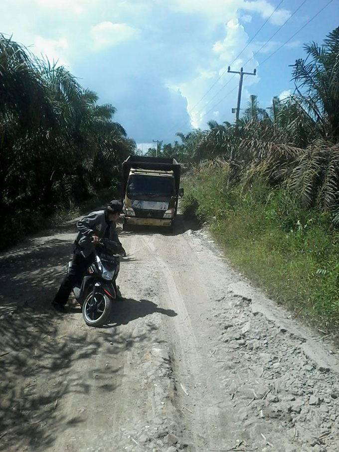 Warga saat melewati Jalan Desa Kuala Tolam, Kecamatan Pelalawan, Kabupaten Pelalawan  yang perlu dilakukan perbaikan, Senin (17/10/2022).