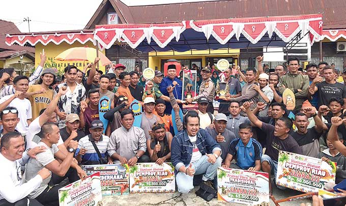 Camat Peranap, Yusri Erdi MPd dan Kapolsek Peranap, Iptu Bahagia Ginting memegang piala bergilir saat foto bersama dengan atlet dan official jalur di halaman Kantor Camat Peranap, Jumat (26/8/2022).