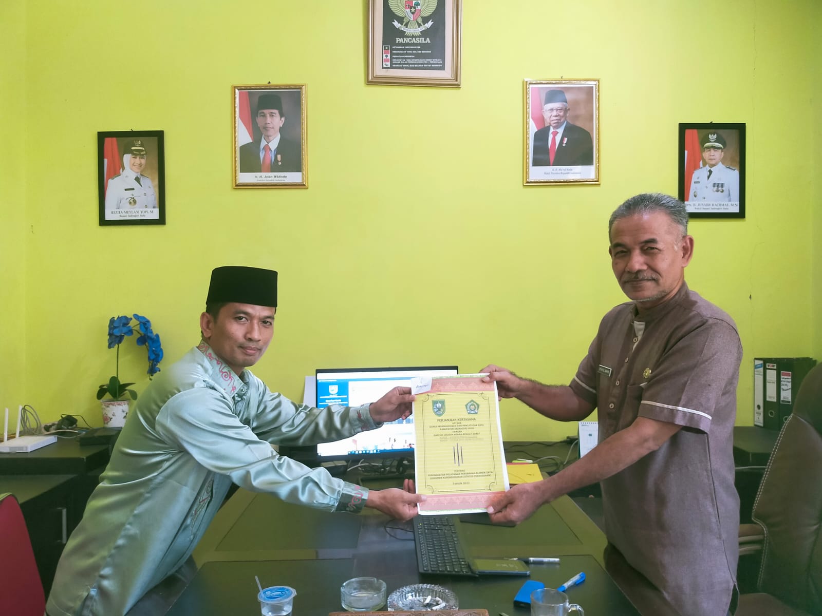 Kadisdukcapil Inhu, Syaiful Bahri SSos (kanan) serahterima berkas kerja sama tentang peningkatan pelayanan perubahan elemen data dokumen kependudukan atas status pernikahan dengan Kepala KUA Rengat Barat, Yusrianto SHI, Jumat (1/7/2022).