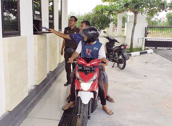 PENGENDARA MOTOR AMBIL STNK: Kajari Kampar Dwi Antoro, menyaksikan pengendara mengambil barang bukti tilang (STNK) di loket Kantor Kejari Kampar, Kamis (31/1/2019). (JPG) HENDRAWAN/RIAU POS