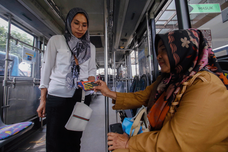 Penumpang melakukan pembayaran nontunai saat menggunakan jasa bus Trans Metro Pekanbaru (TMP), belum lama ini. Pembayaran jasa bus Trans Metro Pekanbaru saat ini sudah tidak memakai uang tunai.