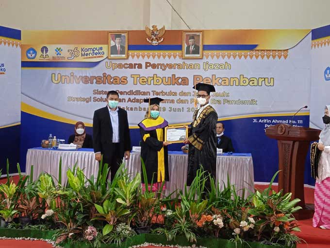 Direktur Universitas Terbuka Pekanbaru Dr Iqbal Miftakhul Mujtahid SIP MSi (kanan) menyerahkan piagam penghargaan kepada wisudawati terbaik dalam upacara penyerahan ijazah Universitas Terbuka Pekanbaru, Sabtu (19/6/2021).