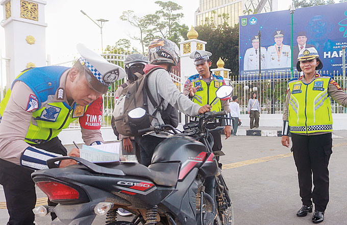 Kasatlantas Polresta Pekanbaru Kompol Birgitta Atvina Wijaya (kanan) bersama petugas Satlantas Polresta Pekanbaru memberikan tilang kepada pelanggar sepeda motor yang tidak memiliki pelat nomor kendaraan di bagian belakang sepeda motor saat melintas di Ka