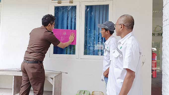 Kasi Pidsus Kejaksaan Negeri (Kejari) Kampar Amri Rahmanto Sayekti memasang stiker penyitaan terhadap PT Johan Sentosa di  Sungai Jernih, Kelurahan Pasir Sialang, Kecamatan Bangkinang, Kabupaten Kampar, Senin (9/1/2023).