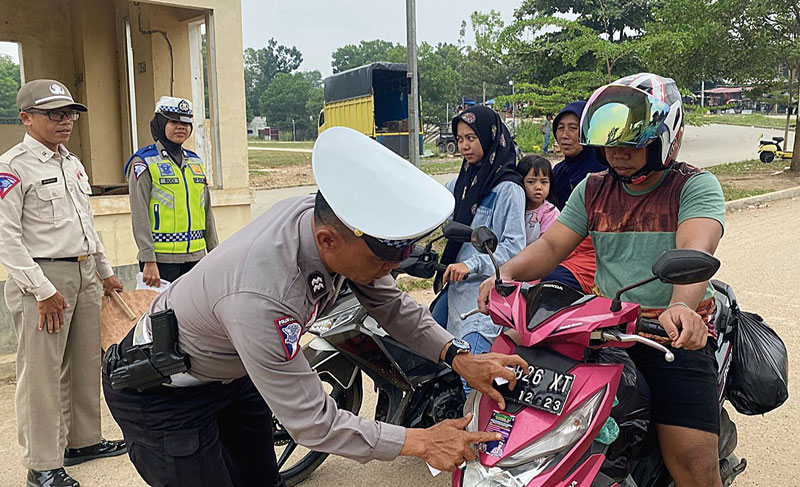 Anggota polisi dari Satlantas Polres Kuansing memasang stiker imbauan tertib lalu lintas ke kendaraan di Telukkuantan, Rabu (6/9/2023).