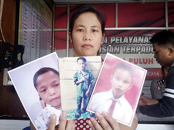SUDAH DITEMUKAN: Ingariya Jega, ibu dari Englitu Telaumbana memegang foto Suprianto Zega (kanan),  Frans Jaya Gea (tengah), dan Englitu Telaumbana (kiri) saat membuat laporan kehilangan di Polsek Limapuluh, Senin (11/3/2019). Ketiga anak tersebut sudah di