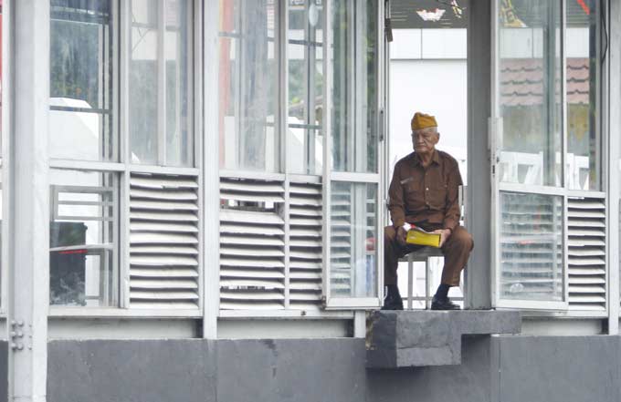 MENUNGGU: Seorang veteran menunggu di halte Trans Metro Pekanbaru, Jalan Sudirman usai mengikuti upacara HUT ke-73 RI, Jumat (17/8/2018). (CF1/MIRSHAL/RIAU POS)