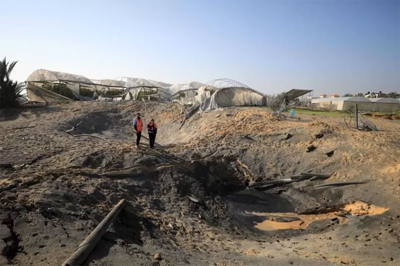 Orang-orang terlihat di sekitar jalan yang rusak setelah serangan udara Israel di kota Khan Younis, Jalur Gaza selatan, Sabtu (2/12/2023).