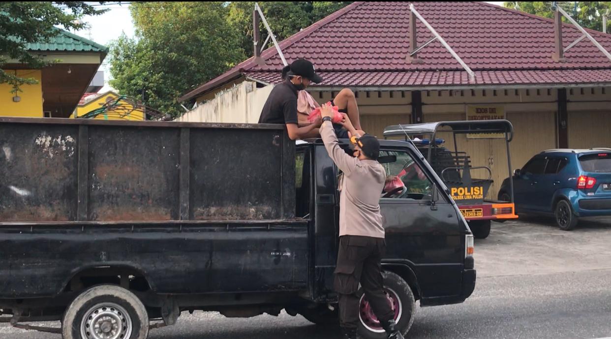 Kapolsek Limapuluh Kompol Sanny Handytio saat memberikan hand sanitizer dan nasi bungkus kepada pengguna jalan di Makopolsek dan seputar Jalan Sisingamangaraja.  (POLSEK LIMAPULUH UNTUK RIAUPOS.CO)