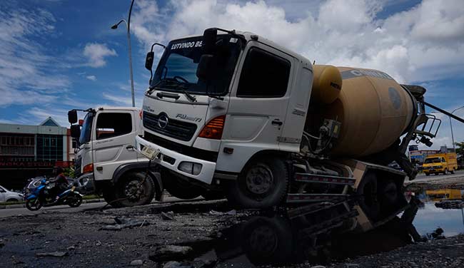 TERPEROSOK: Truk molen terperosok di bahu jalan saat akan memutar arah (U turn) di kawasan pembangunan flyover Pasar Pagi Arengka Jalan Soekarno-Hatta Pekanbaru, Sabtu  (24/11/2018) Kejadian ini mengakibat kemacetan di jalur satu arah di kawasan tersebut.