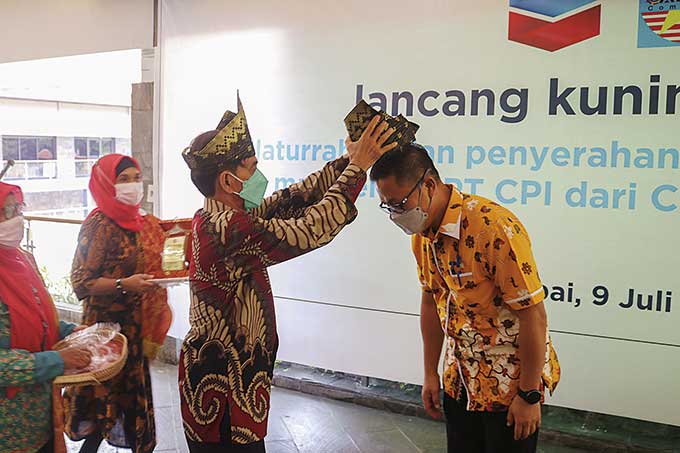 Ketua Calvron Community, Zainuddin Boy memasangkan tanjak kepada Vice President Corporate Affairs PT Chevron Pacific Indonesia Sukamto Tamrin saat acara Lancang Kuning Award di Rumbai Country Club (RCC) kompleks PT CPI Rumbai Pekanbaru, Jumat (9/7/2021).