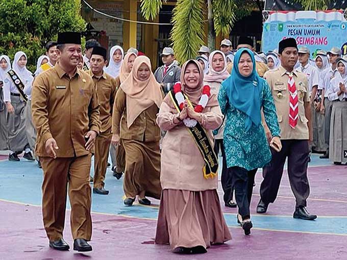 Istri Plt bupati Kuansing,Yulia Suhardiman Amby didampingi Kepala SMAN 1 Telukkuantan Saprianto Eldi berjalan menuju lapangan upacara, Senin (31/10/2022).