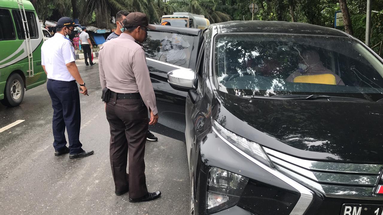 Petugas saat melakukan pengecekan pengemudi kendaraan yang tak mematuhi aturan PSBB untuk menggunakan masker, Kamis (7/5/2020). (SOFIAH/RIAUPOS.CO)