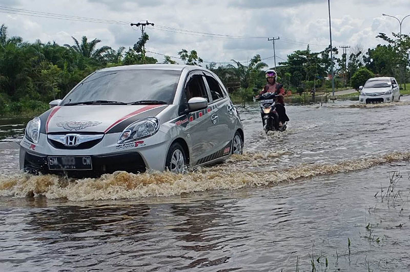 Pengemudi kendaraan bermotor melintasi Jalan Sultan Syarif Hasyim tak jauh dari kantor Bupati, Kecamatan Pangkalan Kerinci, yang digenangi air akibat buruknya pembangunan drainase, pasca diguyur hujan, Selasa (3/11/2020). M AMIN AMRAN/RIAU POS