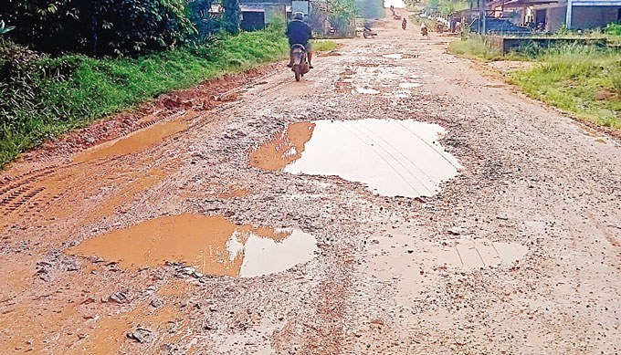 Salah seorang warga melintas di Jalan Poros Desa Kerubung Jaya, Batang Cenaku, yang mengalami rusak, Senin (29/5/2023).