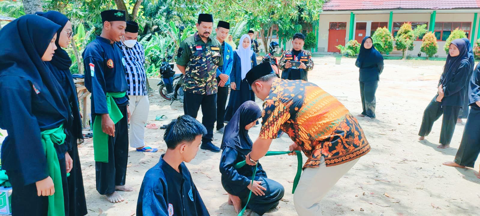 Kepala MAN 4 Pekanbaru Agus Salim Tanjung MA menyerahkan sabuk dari pra polos ke Strip Putih usai Ujian Kenaikan Tingkat Pencak Silat NU Pagar Nusa di halaman MAN 4 Pekanbaru pada, Sabtu (15/10/2022).