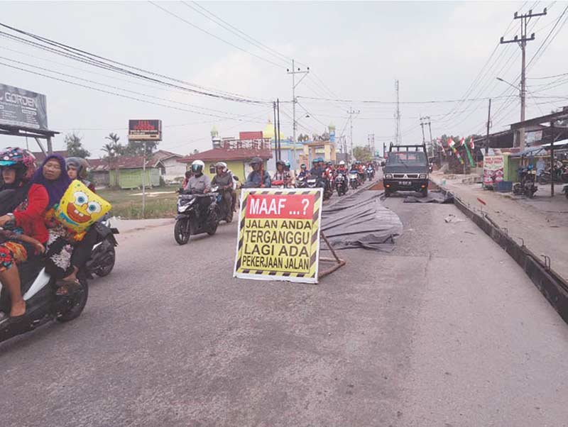 Masyarakat melewati Jalan Syech Umar yang sedang diperbaiki, Senin (19/8/2019).( HASANAL BULKIAH/RIAU POS)